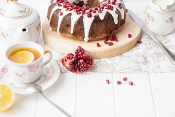 Chocolate muffin round hole (pie, cake, cake) with white icing and pomegranate on a white table. English dish for the holiday, English tea party