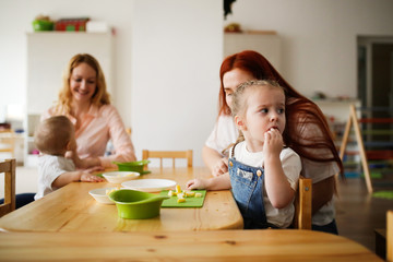 Toddler cuts an apple with her mom’s help