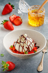 Gourmet burrata cheese with strawberry tartare with mint, honey and balsamic in a light plate on a gray concrete or stone background. Breakfast. Mediterranean (Italian) cuisine. Selective focus