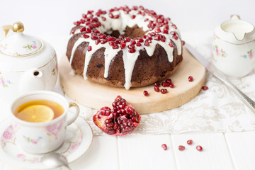 Chocolate Simnel Cake, muffin round hole (pie, cake) with white icing and pomegranate on a white table. English dish for the holiday, English tea party