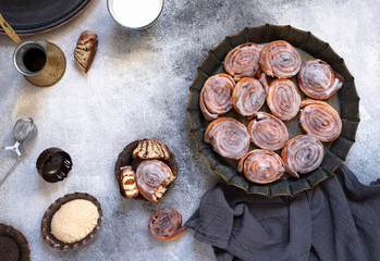 Cinnamon rolls or cinnabon with white cream glaze on a vintage plate, coffee, milk, brown sugar. Homemade traditional bakery dessert. Gray background, top view, copy-space