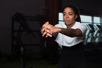 Selective focus of african american attractive woman clenching hands and training in gym
