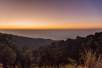 Sunrise at Doi Inthanon, mountain view misty morning of alone tree and many hills with red sky background.