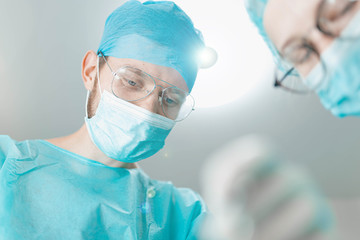 surgeon doctor with assistant student girl in the operating room. first-person view of the patient.