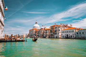 Fototapeta na wymiar Venice, Italy. Tourist gondola trip on Grand Canal. Basilica Santa Maria della Salute against blue sky and white clouds