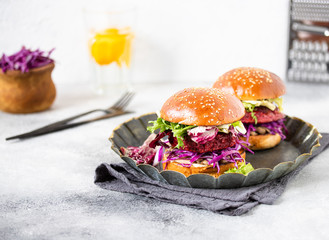 Healthy vegan beetroot burgers with red cabbage and lettuce, served on a vintage plate. Light...