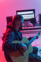 Obraz premium Create music and a recording studio concept - Bearded man guitarist recording electric guitar track in home studio
