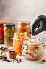 Fermented preserved vegetables food concept. Glass jars with fermented, pickled and canned vegetables  on  kitchen table. Conservation of farm organic seasonal harvest. Healthy homemade food
