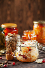 Fermented preserved vegetables food concept. Glass jars with fermented, pickled and canned vegetables  on  kitchen table. Conservation of farm organic seasonal harvest. Healthy homemade food