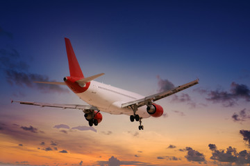A red and white commercial airline landing under a cloudy sky