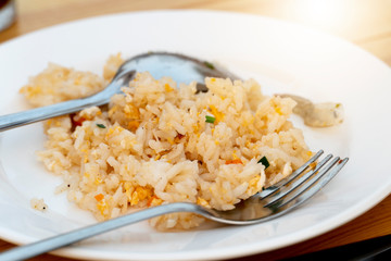 Fried rice on a plate with a spoon and fork being eaten.