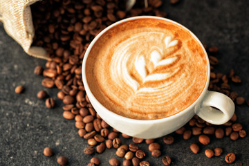 Cup of espresso with coffee beans spilled around it