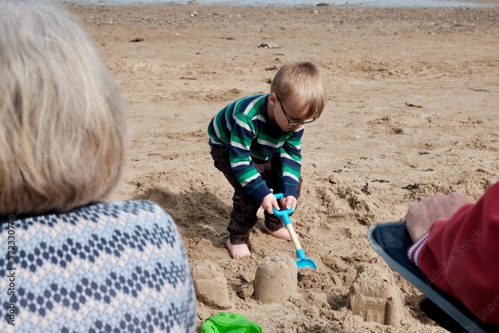 Wall mural boy playing at the beach building sand castles