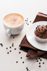 fresh chocolate muffins on white plate near napkin and coffee