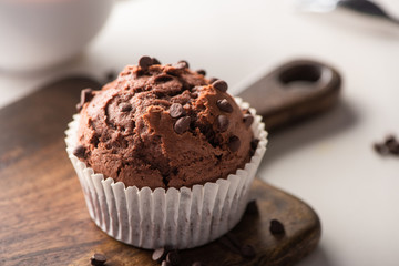 close up view of fresh chocolate muffin on wooden cutting board