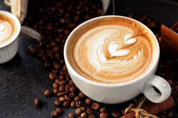 Cup of espresso with coffee beans spilled around it