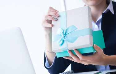 Christmas, any holiday. Office employee received a gift from her colleagues. Closeup woman hands holds gift box on office background.