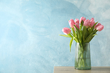 Tulips in vase on wooden table, space for text