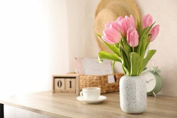 Composition with tulips in vase on wooden background, space for text