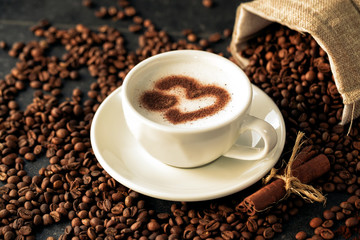 Tide of coffee beans advancing on a cup latte art