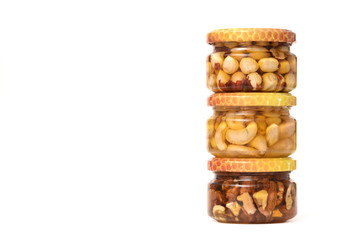Honey with various nuts in glass small jars on a white background. The concept of healthy eating and healthy foods.