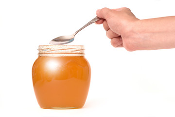 female hand with a spoon and a jar of honey on a white background. The concept of healthy eating and healthy eating.