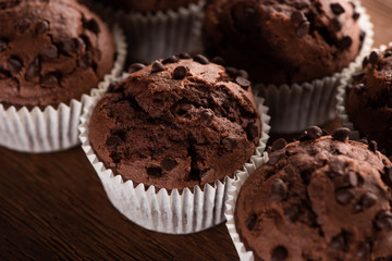 close up view of fresh chocolate muffins on wooden surface