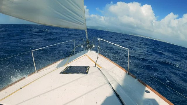 Front of a sailboat is rocking on the waves with splashes