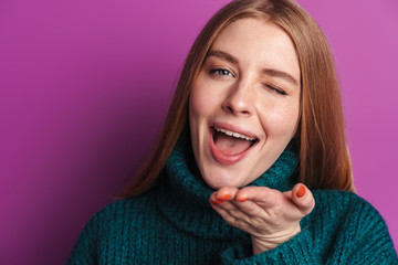 Photo of pleased young woman winking and sending air kiss
