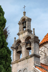 Fototapeta na wymiar Herceg Novi / Montenegro - 05.02.2018: Ancient Byzantine-style church with a bell tower and a set of bells in the southern Adriatic.