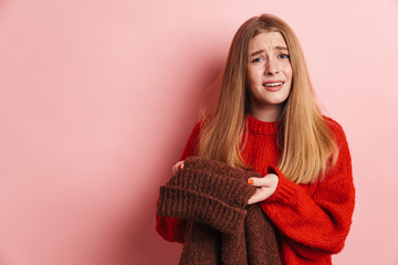 Photo of confused beautiful woman holding sweater and looking at camera