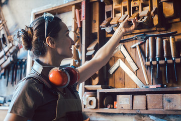 Woman carpenter choosing a tool to work on wood
