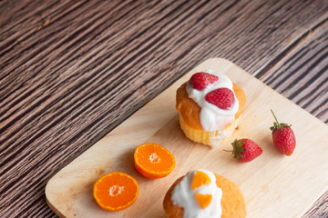 Pieces of orange, strawberry cake on wooden plate, bakery and food.