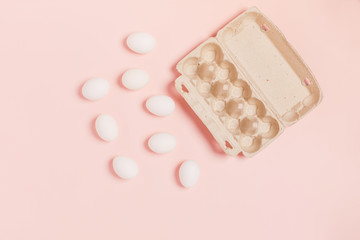 Happy Easter. White eggs located near paper packaging on pink background. Flat lay, top view, copy space.