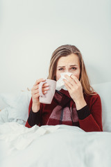Woman with hot tea and the flu lying in bed sick