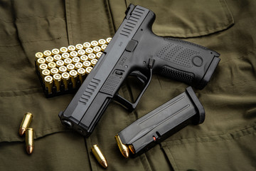 Black modern gun and ammunition for it on a green background. Short-barreled weapons for sports and...