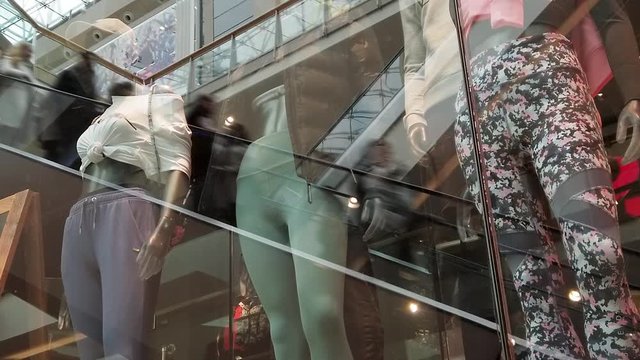 Shop window dummies in a shopping mall.  Clothes shop female display models with a shopping mall reflected in the window.