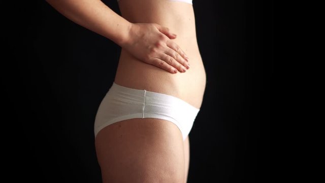 the beauty of pregnancy. the figure of a naked woman in shorts profile in the studio on a black background at a small gestation