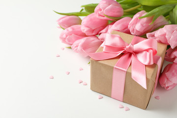Bouquet of tulips, gift box and small hearts on white background, space for text
