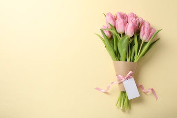 Tulips with blank tag on beige background, space for text