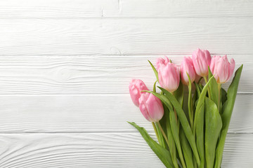 Tulips on white wooden background, space for text
