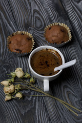 Fototapeta premium Coffee in a white cup. Nearby are muffins, and a dried rose of beige color. On brushed pine boards.