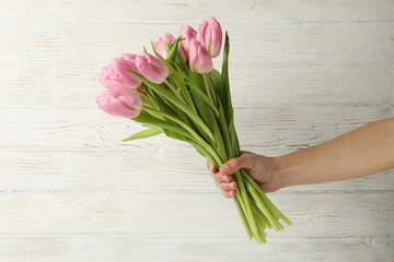 Woman hold bouquet of tulips on wooden background, close up