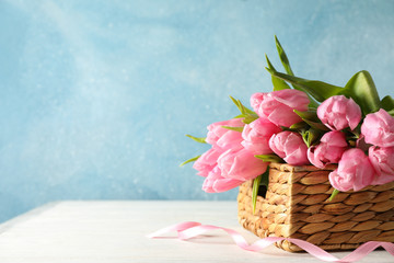 Basket with tulips against blue background, copy space