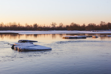 Ice floe in the middle of the river in the rays of the rising sun