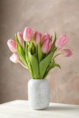 Vase with pink tulips against brown background, space for text