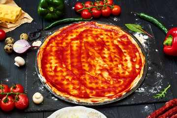 Cooking pizza. Pizza dough topped with tomato sauce and ingredients.