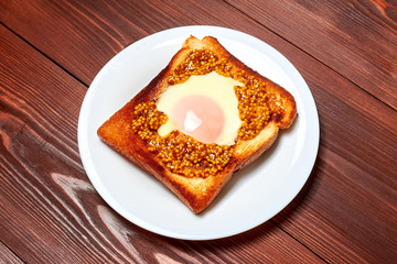 Toast with an egg on a plate on a dark wooden background.
