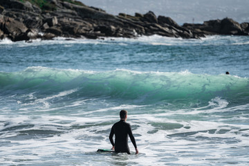 Man entering the sea with his surfboard and waves in the background