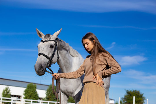 horizontal photo of a young girl with a horse against a blue sky